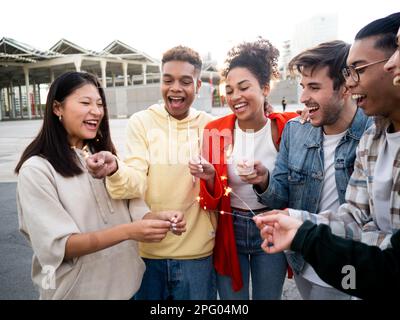 Eine Gruppe verschiedener Millennials, die mit Sparklern feiert. Konzept von Feier und Freundschaft Stockfoto