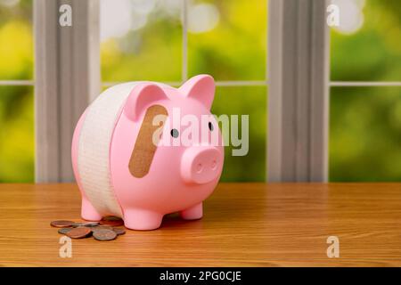 Sparschwein mit Verband und Münzen. Pensionierung, Bankversagen, finanzielle Gesundheit und Planungskonzept. Stockfoto