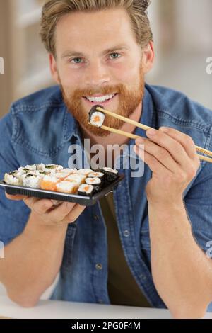 Mann hält Sushi mit Stäbchen Stockfoto