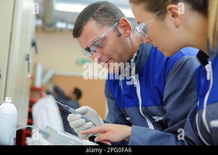 Mann und Frau in Uniform arbeiten mit technischem Objekt Stockfoto