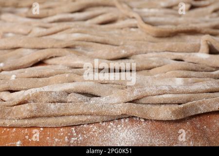 Ungekochtes hausgemachtes Soba (Buchweizennudeln) auf Holztisch, Nahaufnahme Stockfoto