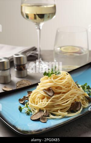 Köstliche Pasta mit Trüffelscheiben und Mikrogreens, serviert auf einem hellgrauen Tisch Stockfoto