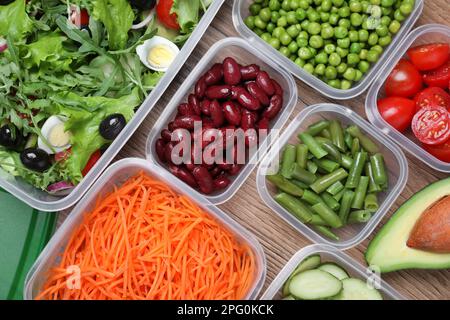 Set aus Kunststoffbehältern mit frischen Lebensmitteln auf Holztisch, flach liegend Stockfoto