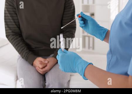 Arzt nimmt Probe für Std-Tests von Mann in Klinik, Nahaufnahme Stockfoto