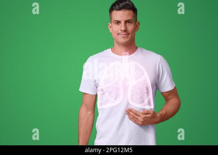 Ein gutaussehender Mann, der die Hand nahe der Brust hält, mit einer Darstellung der Lunge vor grünem Hintergrund Stockfoto
