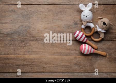 Süßes Babyspielzeug auf Holzhintergrund, flach liegend. Platz für Text Stockfoto