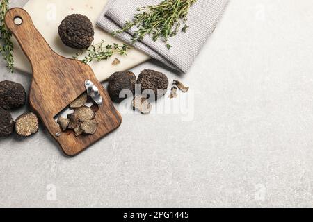 Frische schwarze Trüffel, Scheibe und Thymian auf grauem Tisch, flach liegend. Platz für Text Stockfoto