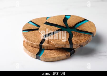 Stilvolle Untersetzer aus Holzbechern auf einem weißen Marmortisch Stockfoto