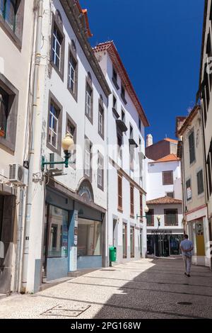 Funchal, Portugal - 20. August 2017: Enge Straße von Funchal, der größten Stadt Madeiras. Ein Mann geht an einem sonnigen Sommertag auf die Straße Stockfoto