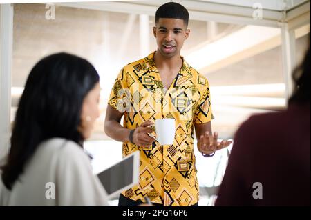 Ich habe mir eine tolle neue Strategie ausgedacht. Ein junger Geschäftsmann, der mit seinen Kollegen in einem Büro spricht. Stockfoto