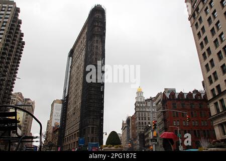 New York, USA. 14. März 2023. Das Flatiron Building im Flatiron District von Manhattan, das teilweise mit Gerüsten versehen ist, ist nach ihm benannt. Das dreieckige Flatiron Building ist eines von New Yorks beliebtesten Wahrzeichen - aber im Moment ist das berühmte „Eisengebäude“ teilweise hinter Gerüsten versteckt und komplett leer. (An dpa: „New Yorks berühmtes „Iron Building“ wird versteigert“) Kredit: Christina Horsten/dpa/Alamy Live News Stockfoto