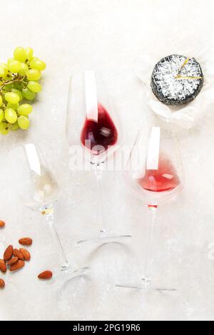 Rosa- und Rotwein serviert mit Käse, Nüssen, Trauben und Gläsern Wein. Köstliche Speisen, Weinsnacks, serviert an Bord. Flach auf einem leichten Ba liegen Stockfoto