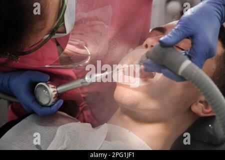 Draufsicht des Zahnputzvorgangs des Patienten. Zähneputzen mit Wasserstrahl und Speichelentferner. Stockfoto