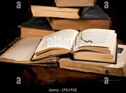 Ein Stapel alter Bücher mit Lesezeichen auf einem Holzhintergrund. Ein Zweig getrockneter Lavendel auf der Seite eines alten Buches. Stockfoto