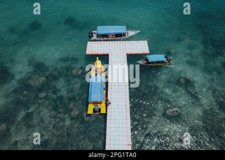 Luftaufnahme auf das natürliche, klare blaue Meer mit schwimmender Brücke und Boot, Perhentian Kecil Island., wunderschöner Reiseort Asien, Sommerurlaub Stockfoto