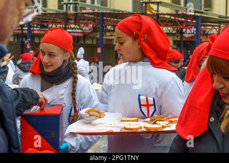 Ivrea, Italien - 19. Februar 2023: Menschen behandeln die Menge mit Essen, eine Tradition, die Teil des historischen Karnevals von Ivrea, Piemont, Norther ist Stockfoto