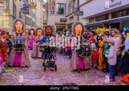 Luzern, Schweiz - 21. Februar 2023: Gruppe von Kostümteilnehmern marschiert auf den Straßen, und Menge, Teil der Kinderparade des Fasnac Stockfoto