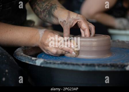 Hände, die einen Topf auf einem Töpferrad machen Stockfoto