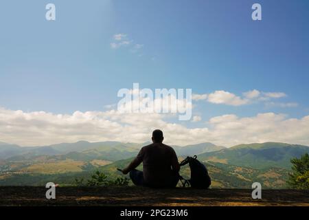 Die Silhouette männlicher Touristen sitzt mit dem Rucksack. Stockfoto