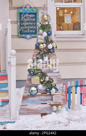 Kasan, Russland - 12. Januar 2023: Kreativer Holzweihnachtsbaum aus Brettern, dekoriert mit Zweigen, Weihnachtsbällen, Geschenkboxen. Eintritt zum Souven Stockfoto