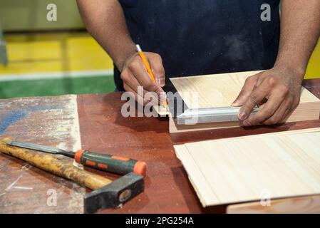 Hände eines Zimmermanns, der Messungen durchführt und sie markiert Stockfoto