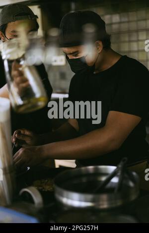 Asiatischer Mann, der in der Restaurantküche kocht. Stockfoto