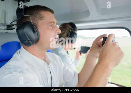 Mann und Frau fotografieren aus dem Fenster eines Flugzeugs Stockfoto