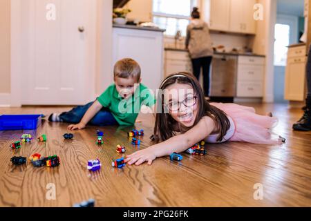 Glückliche Geschwister, die mit Zugspielzeug spielen Stockfoto