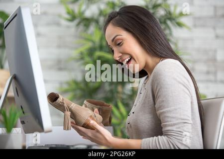 Happy Woman öffnet Paket mit neuen Schuhen, die über das Internet bestellt werden Stockfoto