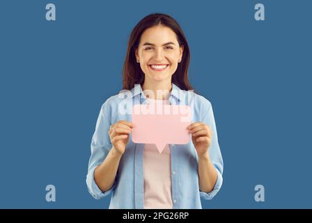 Porträt einer schönen, fröhlich lächelnden jungen brünetten Frau in lässiger Kleidung mit leerer Papierbotschaft für Werbung. Stockfoto