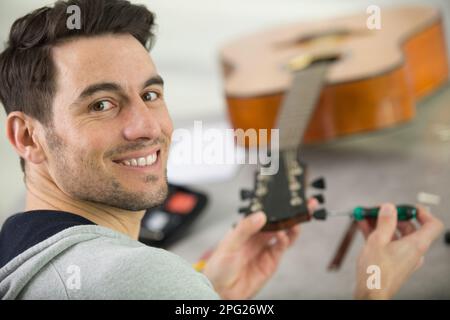 Junge gut aussehende Werkstatt Reparatur Gitarre Stockfoto