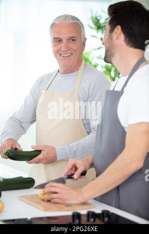 Hipster-Sohn mit seinem Senior-Vater, der in der Küche kocht Stockfoto