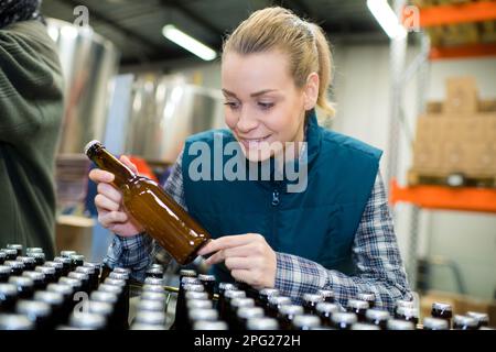 Fabrikarbeiter, der das Förderband mit Bierflaschen bedient Stockfoto