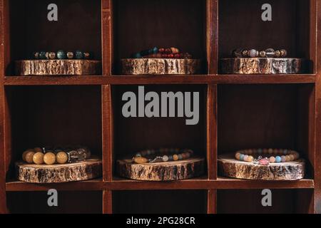 Armbänder und Perlen in verschiedenen Farben auf einem Ständer aus Naturholz Stockfoto