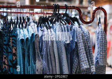 Blaue Frauenkleidung hängt an einem Kleiderbügel hintereinander. Modekollektion Stockfoto