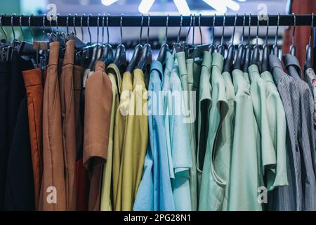 Beige blau Grün Damenbekleidung Kleider Jacken hängen an einem Kleiderbügel in Folge. Modekollektion Stockfoto