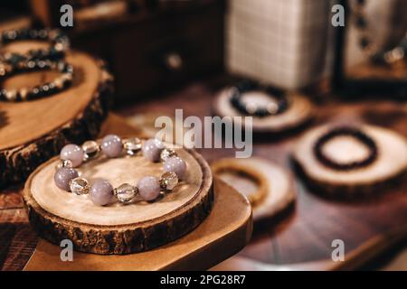 Armbänder aus rosafarbenen Steinperlen auf einem Ständer aus natürlichem Holz Stockfoto