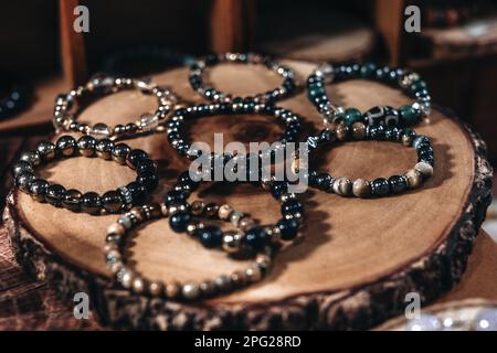 Armbänder mit dunklen Steinperlen auf einem Ständer aus natürlichem Holz Stockfoto