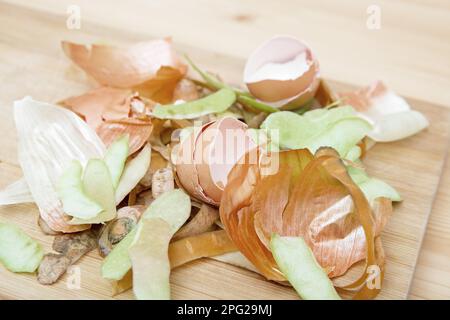 Kompost aus Schalen von Gemüse, Früchten und Eierschalen auf einem Schneidebrett und einem Holztisch. Das Konzept des abfallfreien Verbrauchs und des umweltfreundlichen Verhaltens Stockfoto