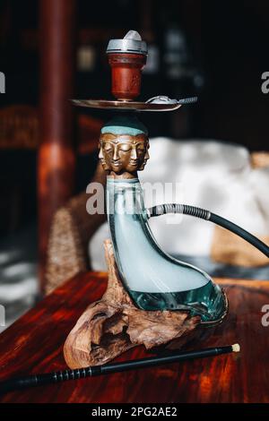 Kreative seltene exklusive goldene buddha-Hookah steht auf einem Holztisch. Vertikal Stockfoto