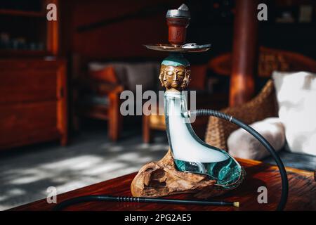 Kreative seltene exklusive goldene buddha-Hookah steht auf einem Holztisch Stockfoto