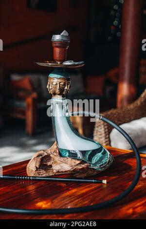 Kreative seltene exklusive goldene buddha-Hookah steht auf einem Holztisch. Vertikal Stockfoto