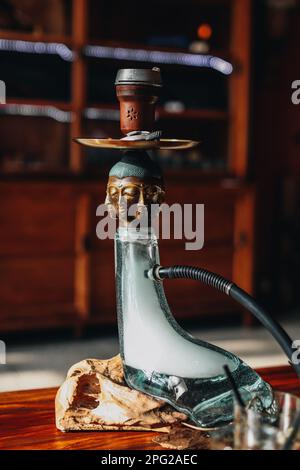 Kreative seltene exklusive goldene buddha-Hookah steht auf einem Holztisch. Vertikal Stockfoto