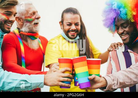 Multirassische Schwule tragen Schutzmasken, während sie bei der PRIDE-Parade im Freien mit Regenbogenbrille jubeln - Fokus auf Brille Stockfoto