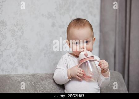 Süßes kleines Mädchen mit Flasche und Trinkwasser. Stockfoto