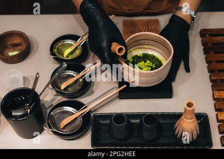 Zubereitung von grünem Matcha-Tee. Stillleben mit traditionellem japanischem Bio-Zubehör auf dem Tisch. Stockfoto