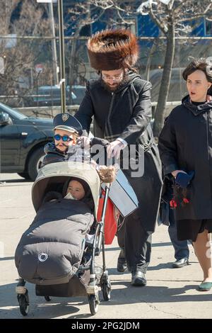 Eine orthodoxe jüdische Familie feiert Purim, den Vater mit seinem streimeligen Pelzhut und den Sohn mit einem Kostüm. In Brooklyn, New York. Stockfoto