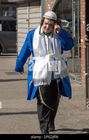 Ein junger Mann in seinem farbenfrohen Purim-Kostüm dreht seine Péyus. Auf Der Lee Ave. In Brooklyn, New York City. Stockfoto