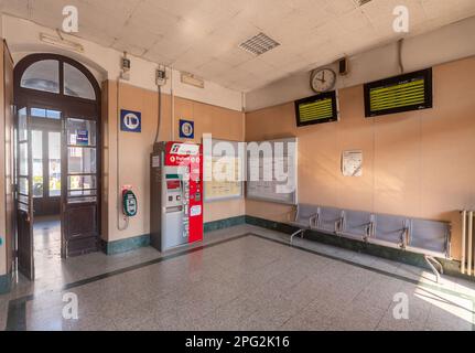 Savigliano, Cuneo, Italien - 20. März 2023: Warteraum mit automatischem Fahrkartenautomaten und Zugfahrplan-LED-Anzeige in der Bahn Stockfoto