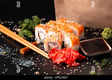 Die Auswahl verschiedener japanischer Sushi- und Brötchensorten. Auf dunklem rustikalem Hintergrund. Rollt auf dunklem Hintergrund. Meeresfrüchte mit Stäbchen. Stockfoto